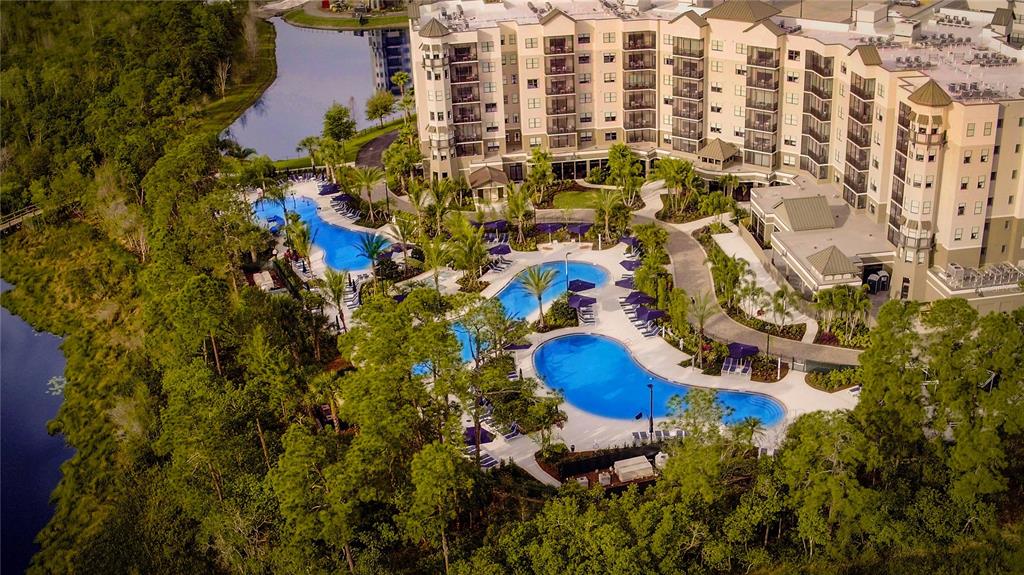 An aerial view shows a large resort hotel with multiple swimming pools and surrounding woods — 14501 GROVE RESORT AVENUE UNIT 3538, WINTER GARDEN, FL