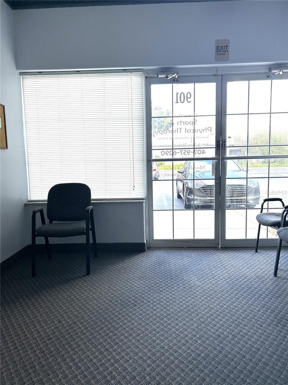 A waiting area features a dark chair, carpeted flooring, and glass doors leading outside — 901 N CENTRAL AVENUE, KISSIMMEE, FL