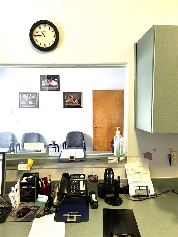A reception desk area features a wall clock, office supplies, a telephone, and a window — 901 N CENTRAL AVENUE, KISSIMMEE, FL