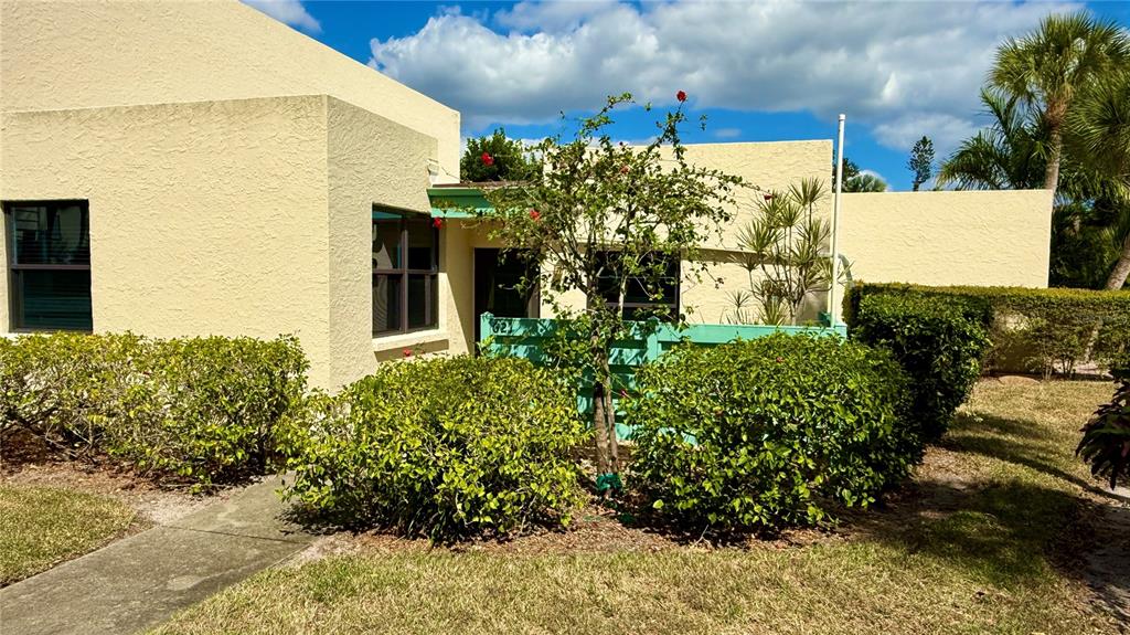 A light yellow stucco building features a green fence and a small tree with flowers — 621 SPRING LAKES BOULEVARD UNIT 621, BRADENTON, FL