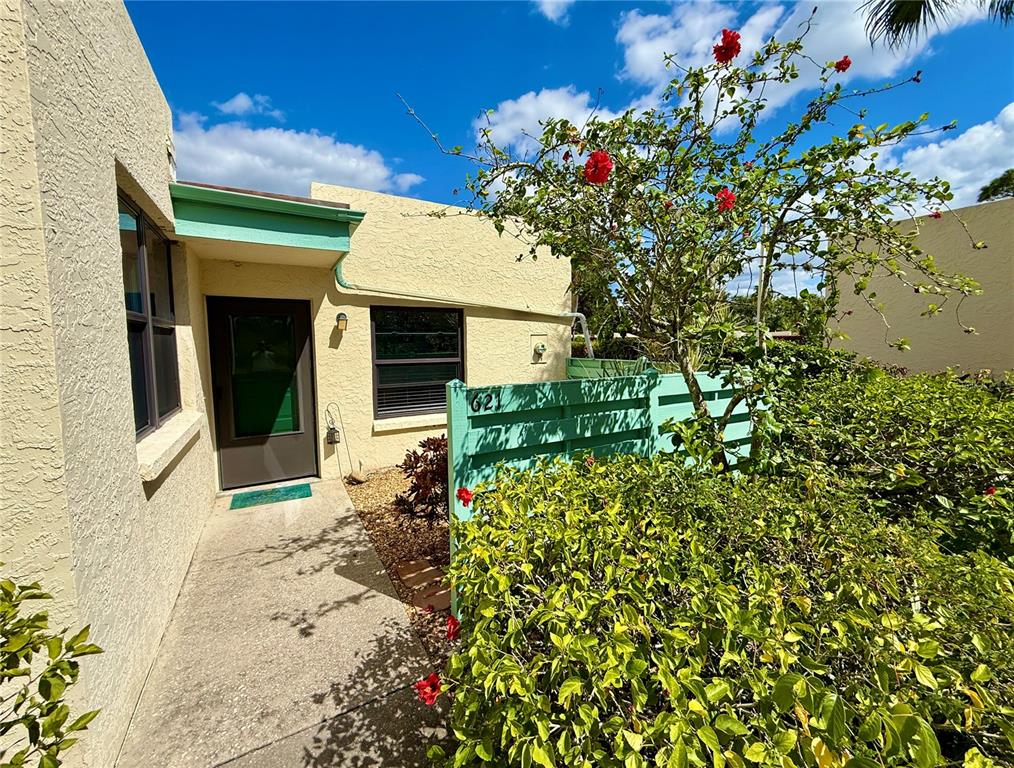 A beige stucco building exterior features a front door, a walkway, and a privacy fence — 621 SPRING LAKES BOULEVARD UNIT 621, BRADENTON, FL