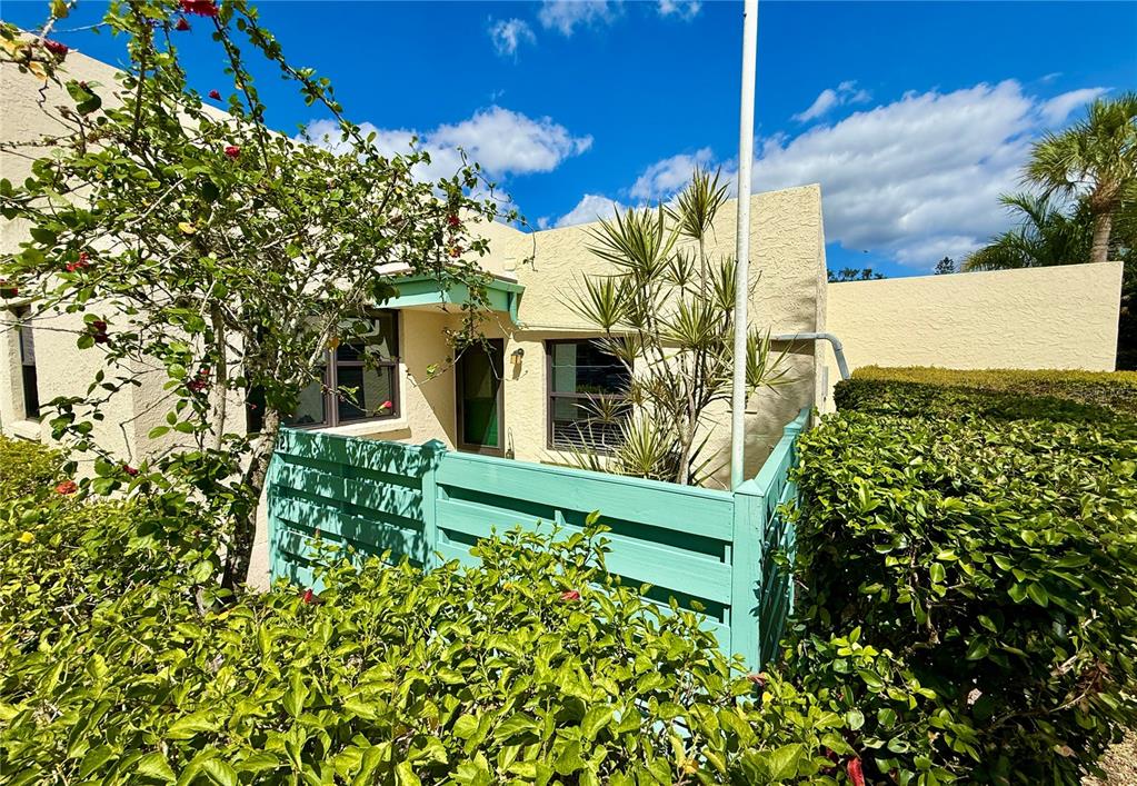 A light-colored building exterior features a turquoise privacy fence and lush green landscaping — 621 SPRING LAKES BOULEVARD UNIT 621, BRADENTON, FL