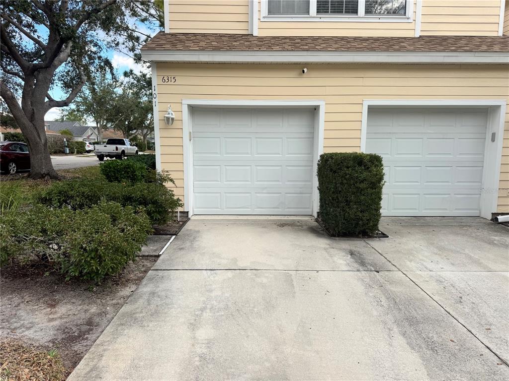 A two-car garage with white doors and a concrete driveway in front of a house — 6315 ROSEFINCH COURT UNIT 101, LAKEWOOD RANCH, FL