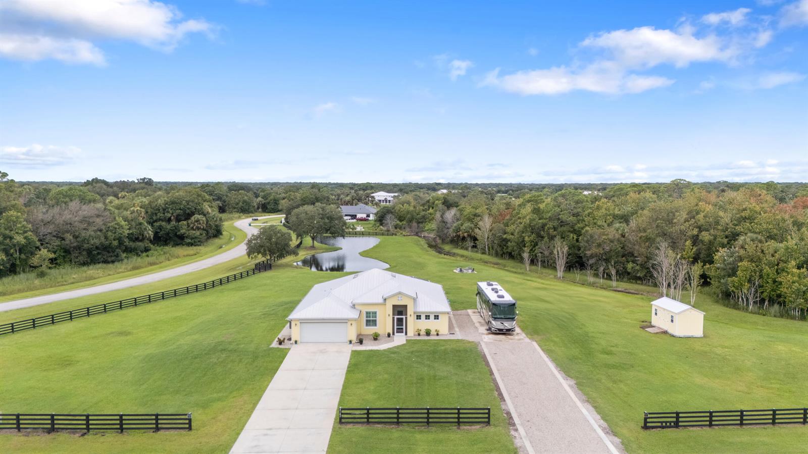 An aerial view shows a house with a metal roof, a driveway, and an RV — 2143 SE 137th Way, Okeechobee FL 34974, OKEECHOBEE, FL