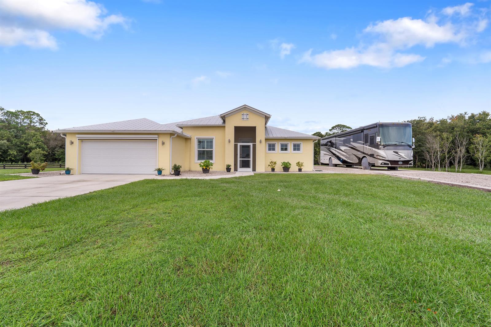 A yellow single-story house with a metal roof and an attached RV parked on the side — 2143 SE 137th Way, Okeechobee FL 34974, OKEECHOBEE, FL