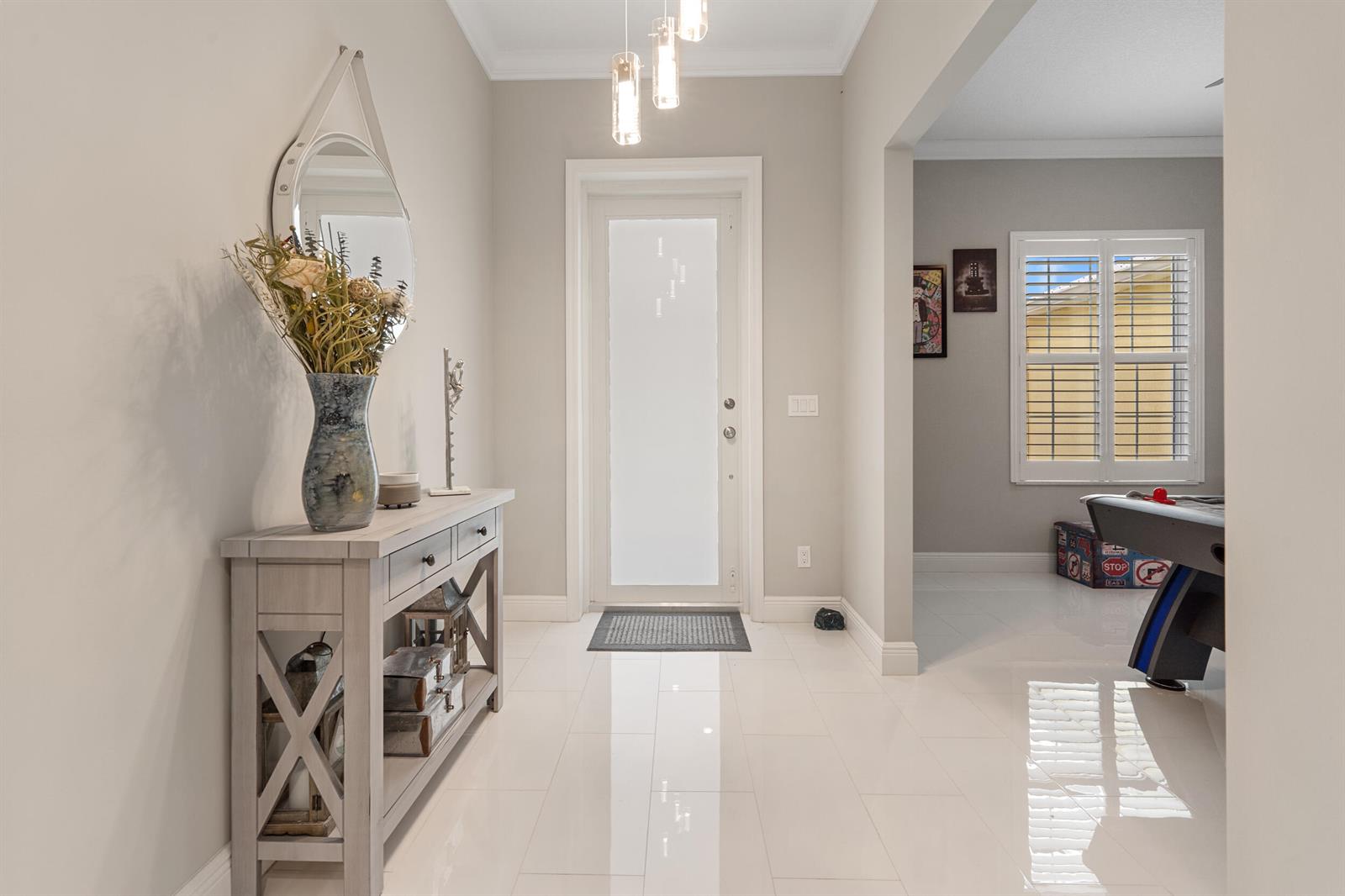 A bright entryway features white tile floors, a console table, and a frosted glass door — 2143 SE 137th Way, Okeechobee FL 34974, OKEECHOBEE, FL