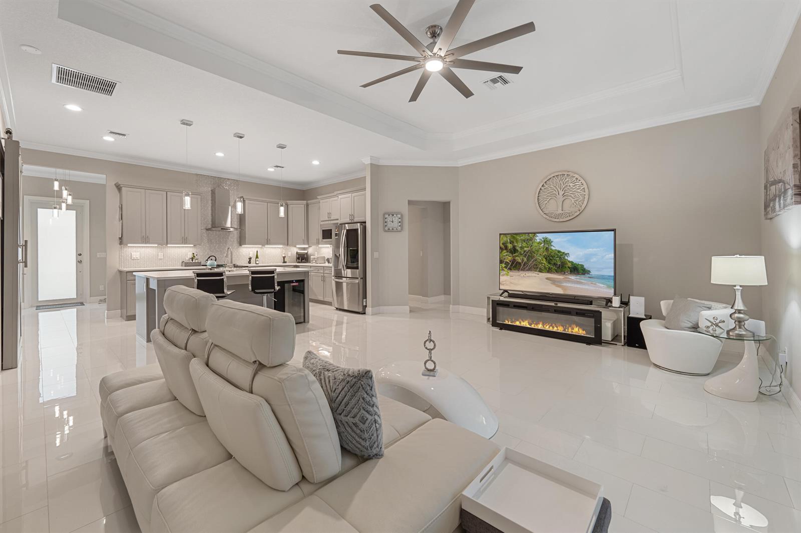 A modern open-concept living room and kitchen featuring white tile floors and neutral cabinetry — 2143 SE 137th Way, Okeechobee FL 34974, OKEECHOBEE, FL
