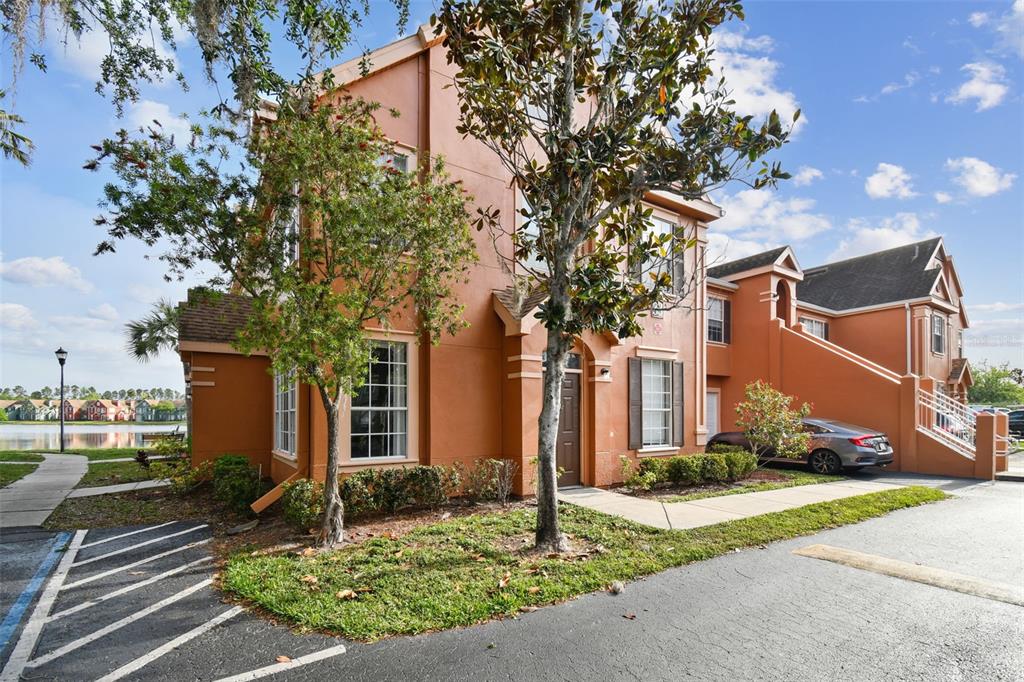 A two-story orange stucco townhouse with a front entrance and a parked silver car — 9740 LAKE CHASE ISLAND WAY UNIT 9740, TAMPA, FL
