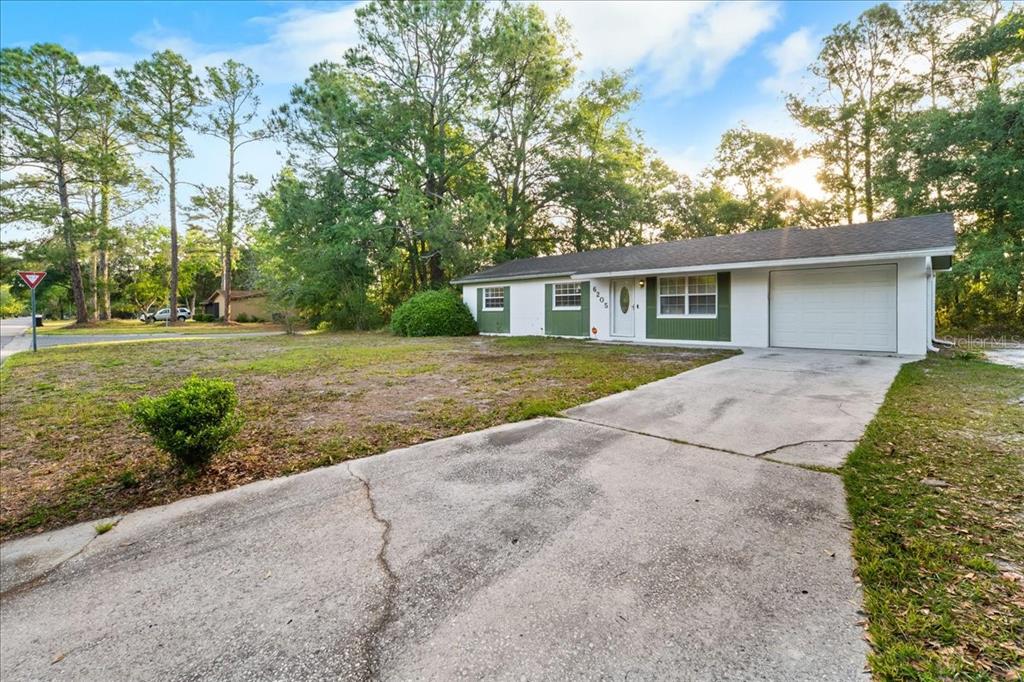 A single-story house with a white exterior, green shutters, and a concrete driveway — 6205 NW 26TH TERRACE, GAINESVILLE, FL