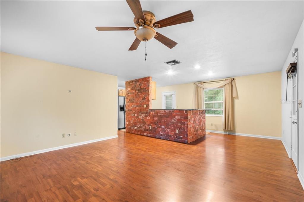 A living room with wood flooring, a ceiling fan, and a brick-faced kitchen island — 6205 NW 26TH TERRACE, GAINESVILLE, FL