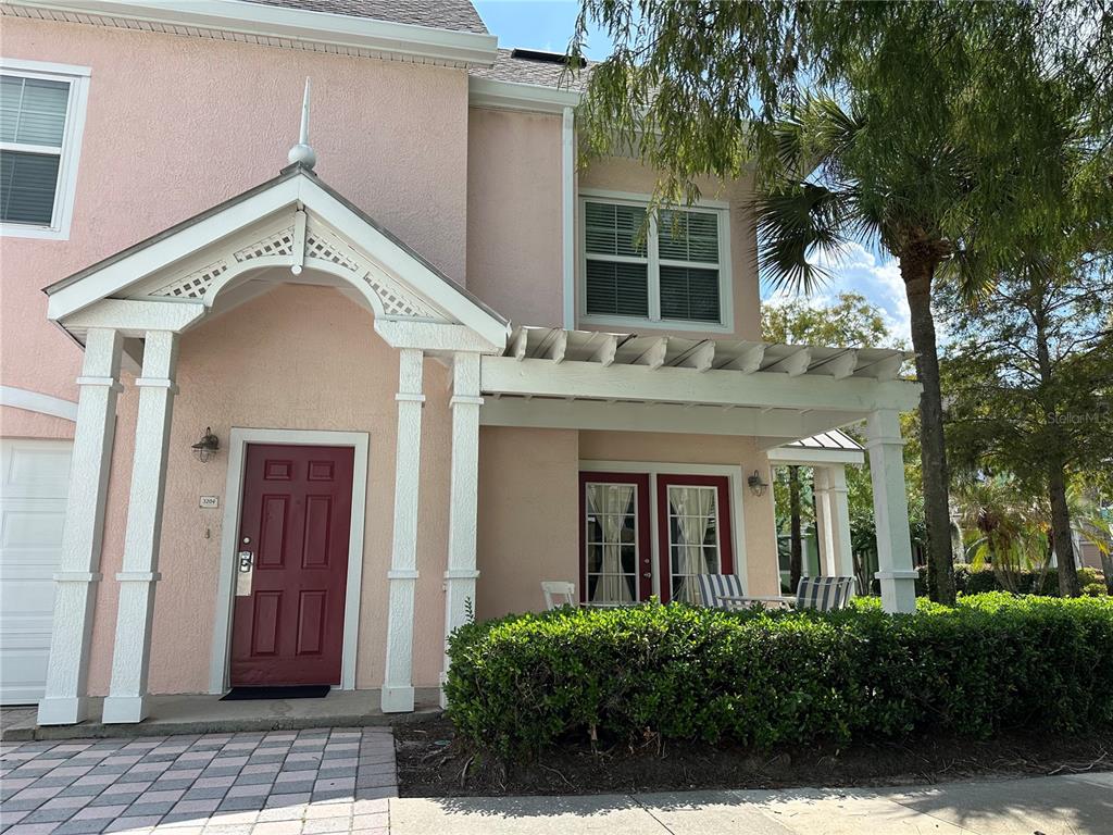 A two-story pink stucco townhouse features a red front door and a covered front porch — 3006 BONFIRE BEACH DRIVE UNIT 204, KISSIMMEE, FL