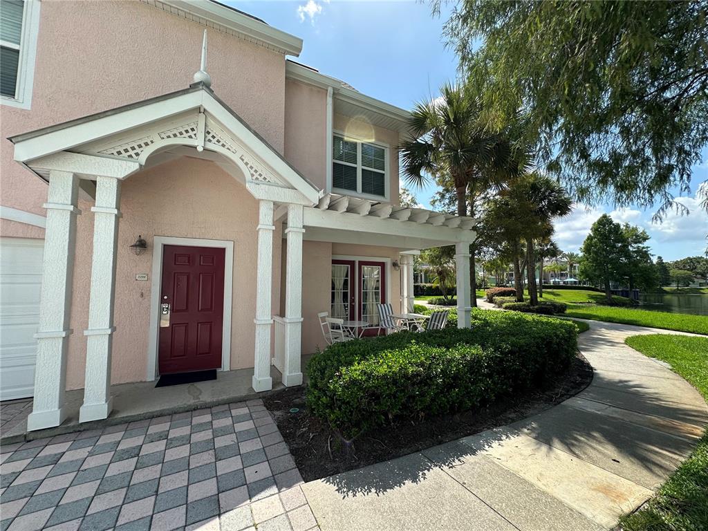 A pink two-story townhouse features a red front door, a covered porch, and a walkway — 3006 BONFIRE BEACH DRIVE UNIT 204, KISSIMMEE, FL