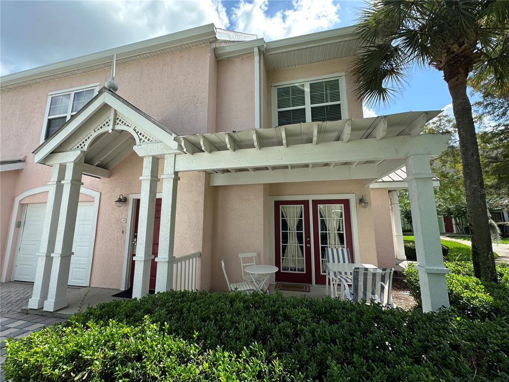 A pink two-story townhouse exterior features a white pergola over a small patio area — 3006 BONFIRE BEACH DRIVE UNIT 204, KISSIMMEE, FL