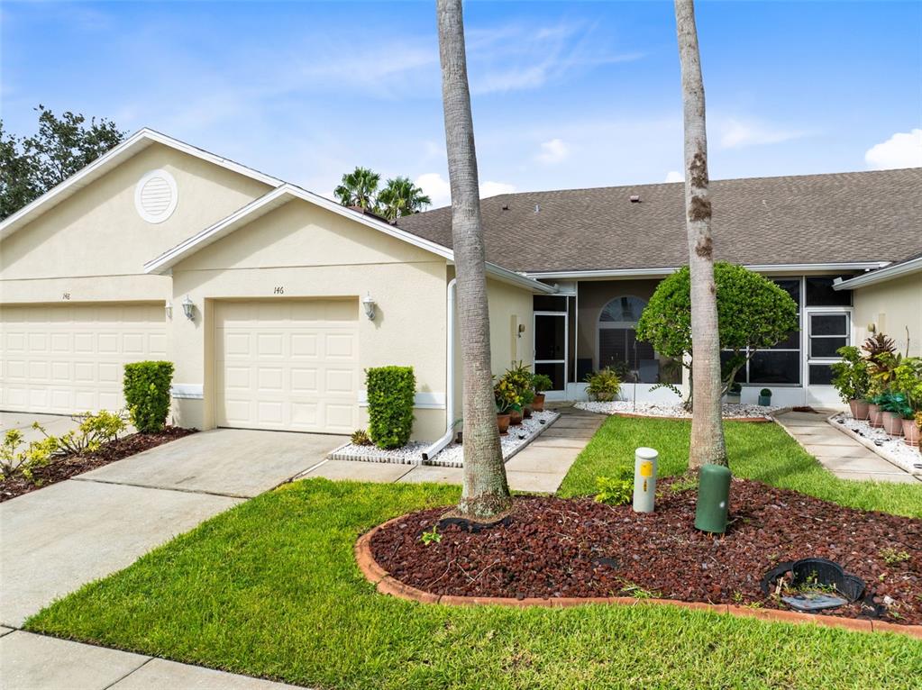 A beige single-story house features a two-car garage, palm trees, and a landscaped front yard — 146 CLUB VILLAS LANE, KISSIMMEE, FL