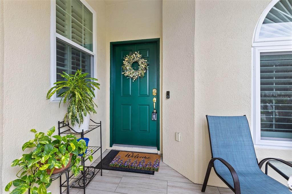A green front door with a wreath sits on a porch with potted plants — 146 CLUB VILLAS LANE, KISSIMMEE, FL