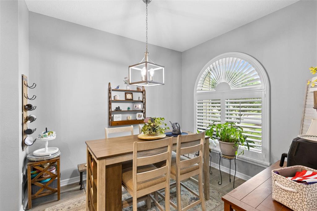 A dining room features a wooden table, chairs, a wall-mounted shelf, and an arched window — 146 CLUB VILLAS LANE, KISSIMMEE, FL