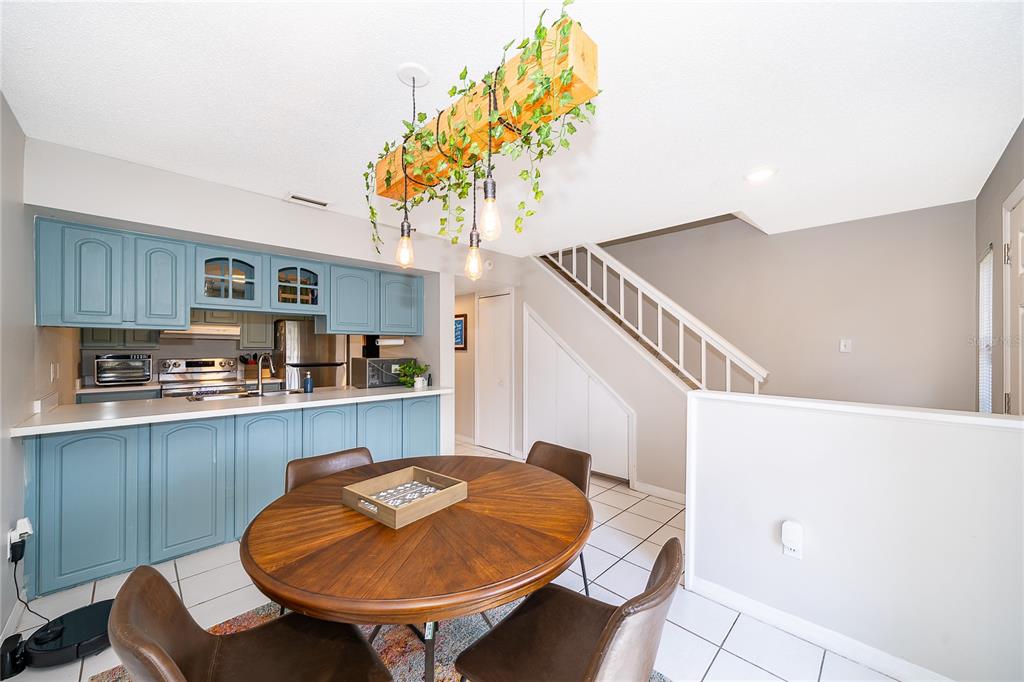 A dining area with a round wooden table sits before a kitchen with blue cabinets — 1073 LOVE LANE UNIT 1, APOPKA, FL