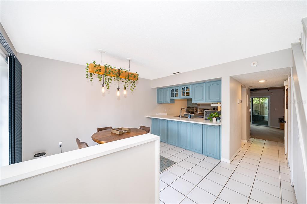 A dining area with a wood-beam light fixture sits next to a blue-cabinet kitchen — 1073 LOVE LANE UNIT 1, APOPKA, FL
