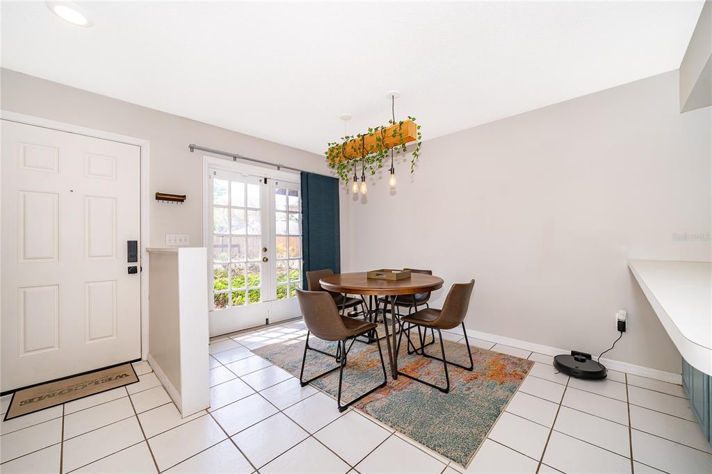 A dining area with a round table, chairs, a hanging light fixture, and tile flooring — 1073 LOVE LANE UNIT 1, APOPKA, FL