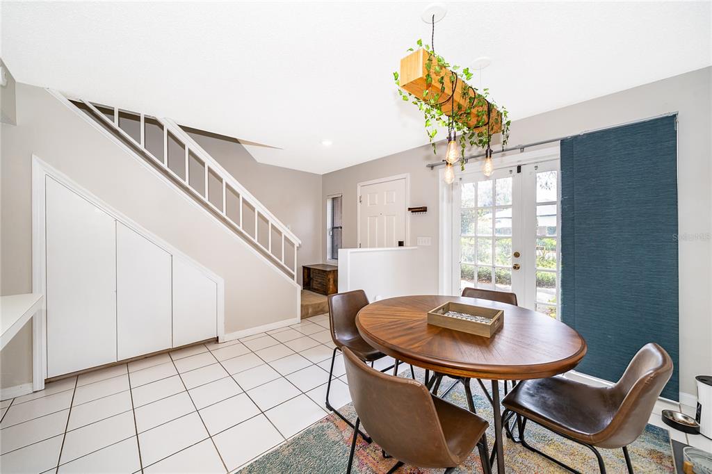 A dining area features a round wooden table, chairs, a hanging planter, and a staircase — 1073 LOVE LANE UNIT 1, APOPKA, FL