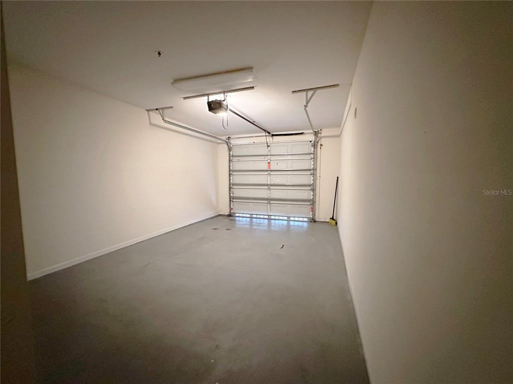 An empty garage with a concrete floor, white walls, and a sectional overhead door — 12843 MADISON POINTE CIRCLE UNIT 201, ORLANDO, FL