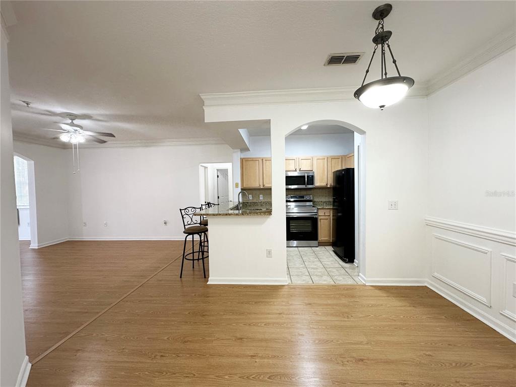 A dining area opens to a kitchen with a breakfast bar and light wood cabinets — 12843 MADISON POINTE CIRCLE UNIT 201, ORLANDO, FL