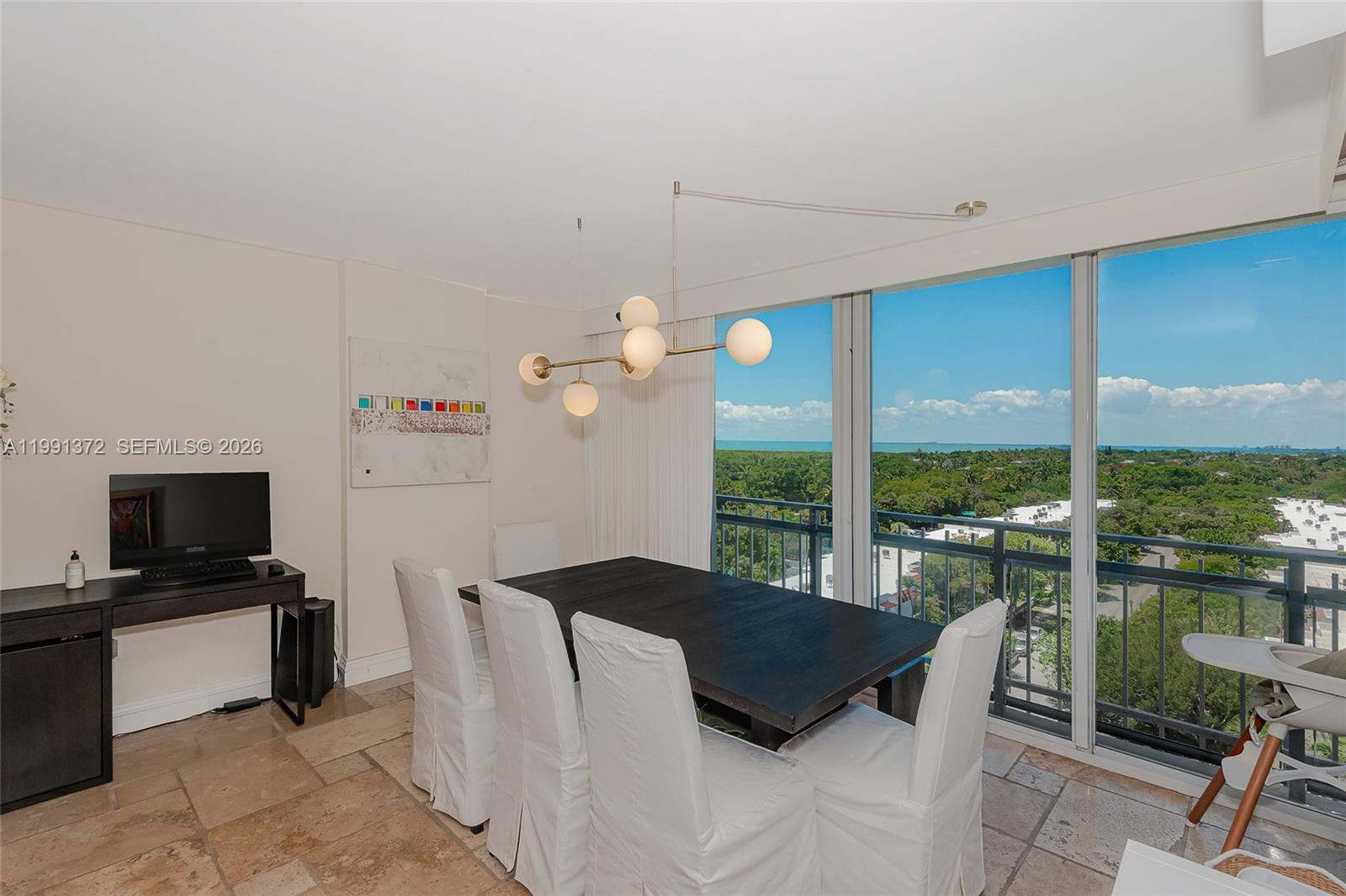 A dining room features a dark wood table, white slipcovered chairs, and floor-to-ceiling windows — 600 Grapetree Dr, Key Biscayne FL 33149, KEY BISCAYNE, FL