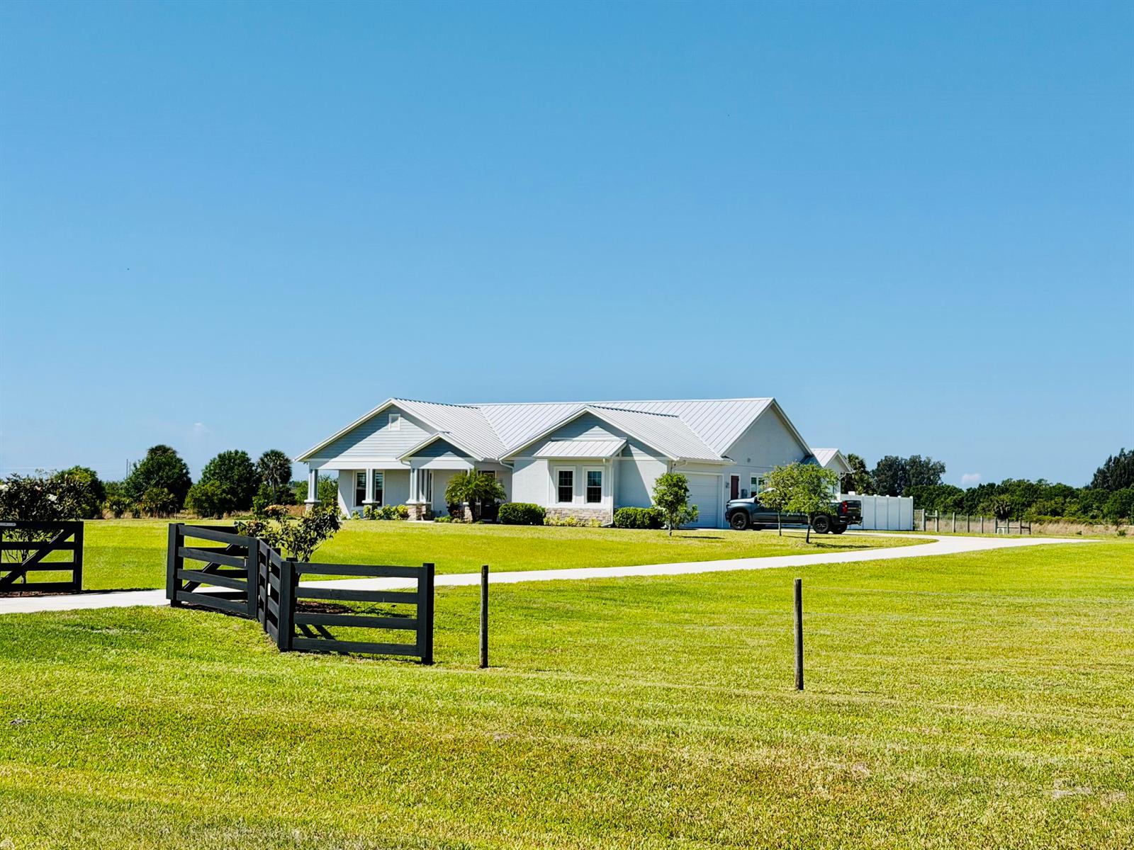 A light-colored single-story house with a metal roof sits on a large grassy lot — 6612 SE 26th Trail, Okeechobee FL 34974, OKEECHOBEE, FL