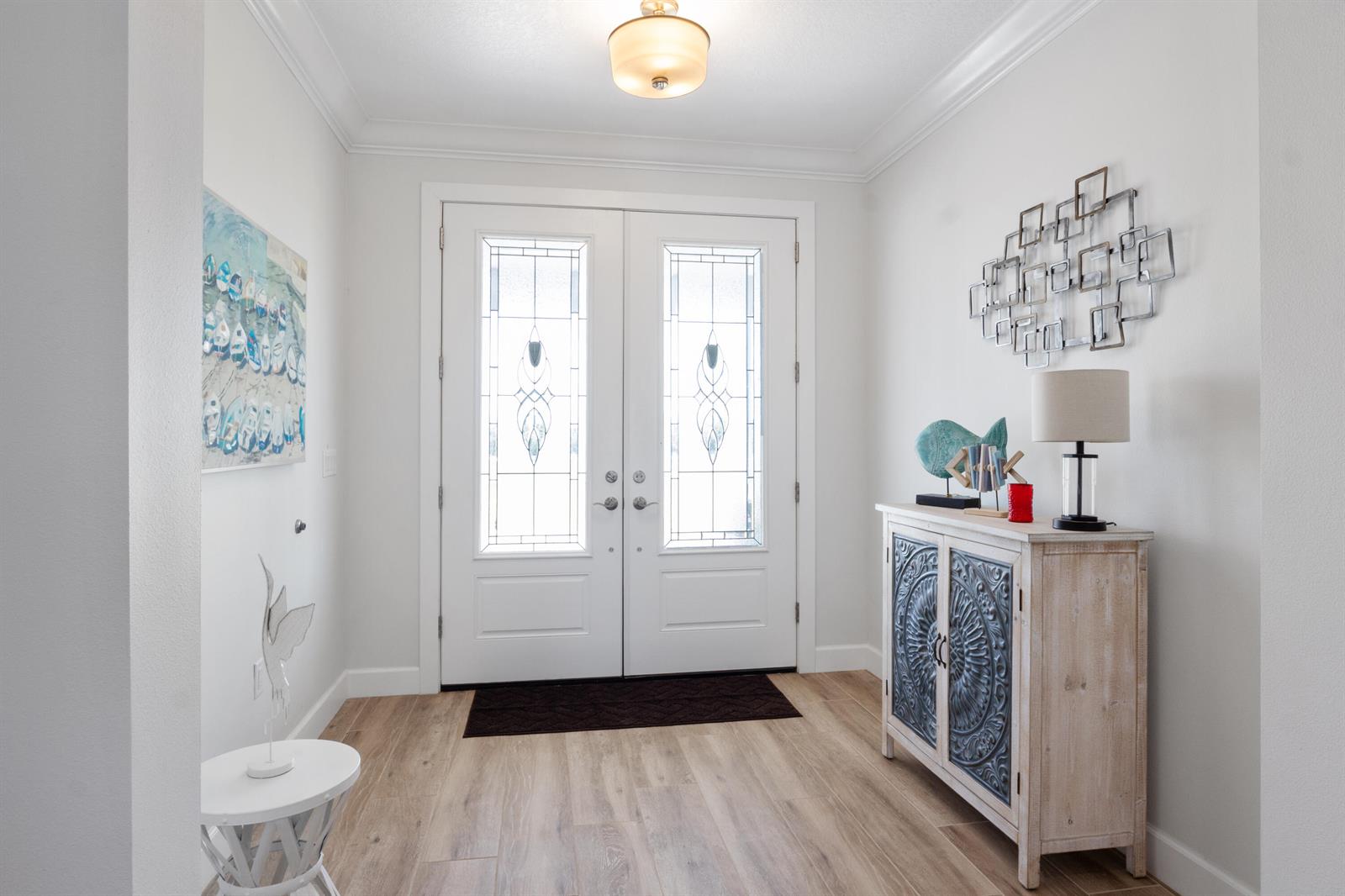 A bright entryway features double glass-paneled doors, light wood flooring, and a decorative console table — 6612 SE 26th Trail, Okeechobee FL 34974, OKEECHOBEE, FL