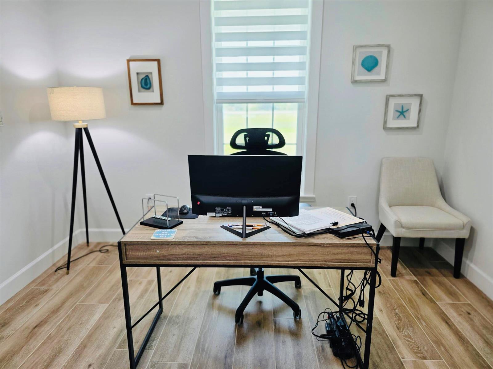 A home office features a wooden desk, an ergonomic chair, a floor lamp, and wall art — 6612 SE 26th Trail, Okeechobee FL 34974, OKEECHOBEE, FL
