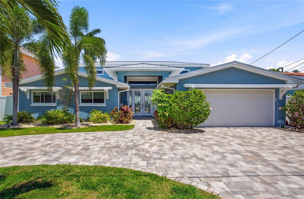 A blue single-story house with a paved driveway, palm trees, and a two-car garage — 547 JOHNS PASS AVENUE, MADEIRA BEACH, FL