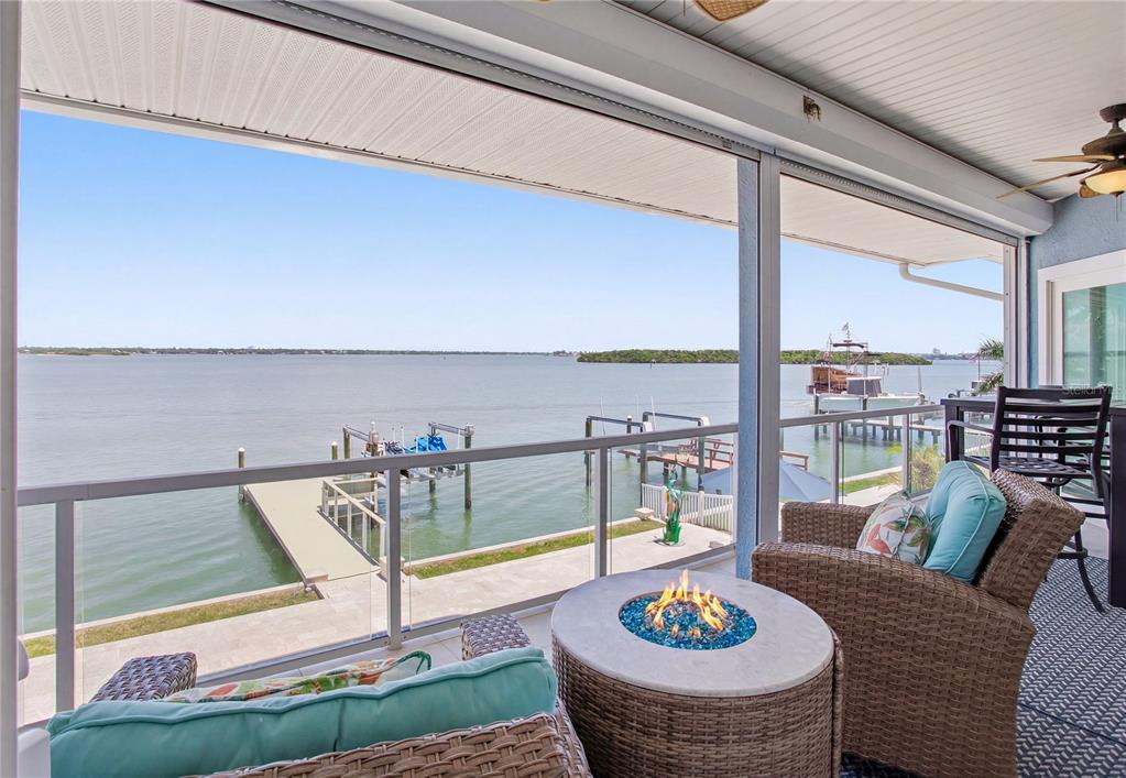 A covered balcony features a fire pit, wicker furniture, and a view of the water — 547 JOHNS PASS AVENUE, MADEIRA BEACH, FL