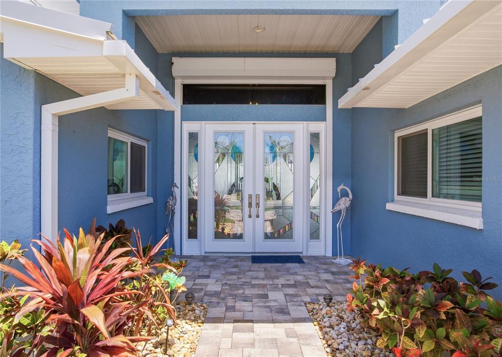 The front entrance features double glass doors, a stone walkway, and blue exterior walls — 547 JOHNS PASS AVENUE, MADEIRA BEACH, FL