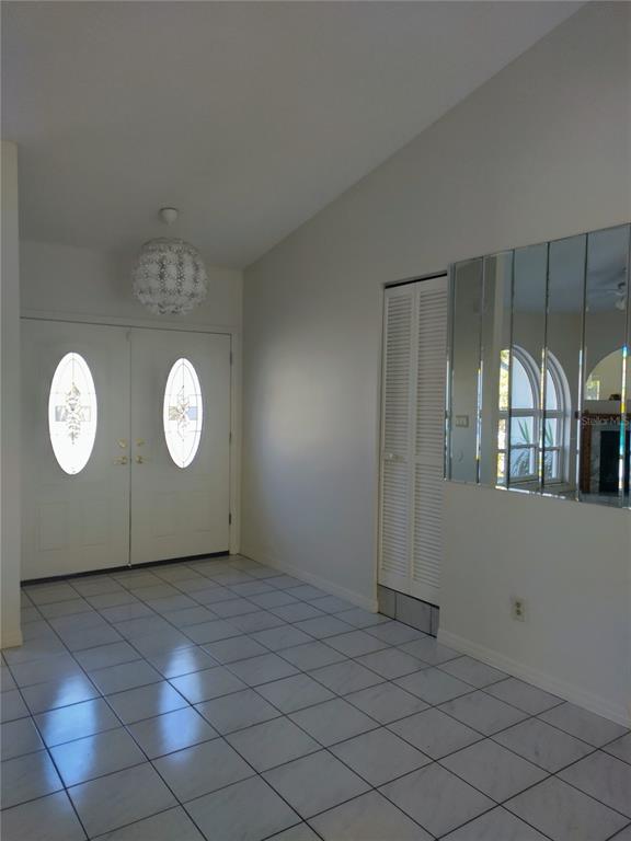 An entryway features white tiled floors, double front doors, a louvered closet, and mirrored wall panels — 1936 SPANISH OAKS DRIVE S, PALM HARBOR, FL