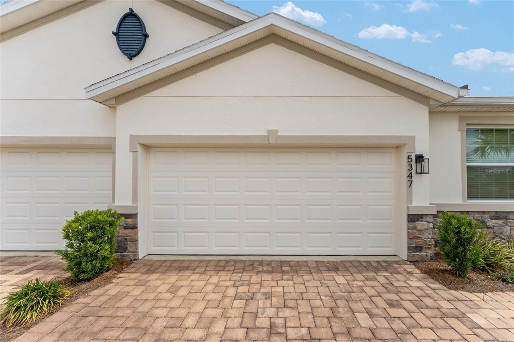 A beige house exterior features a two-car garage, stone accents, and a paved driveway — 5347 NW 46TH LANE ROAD, OCALA, FL