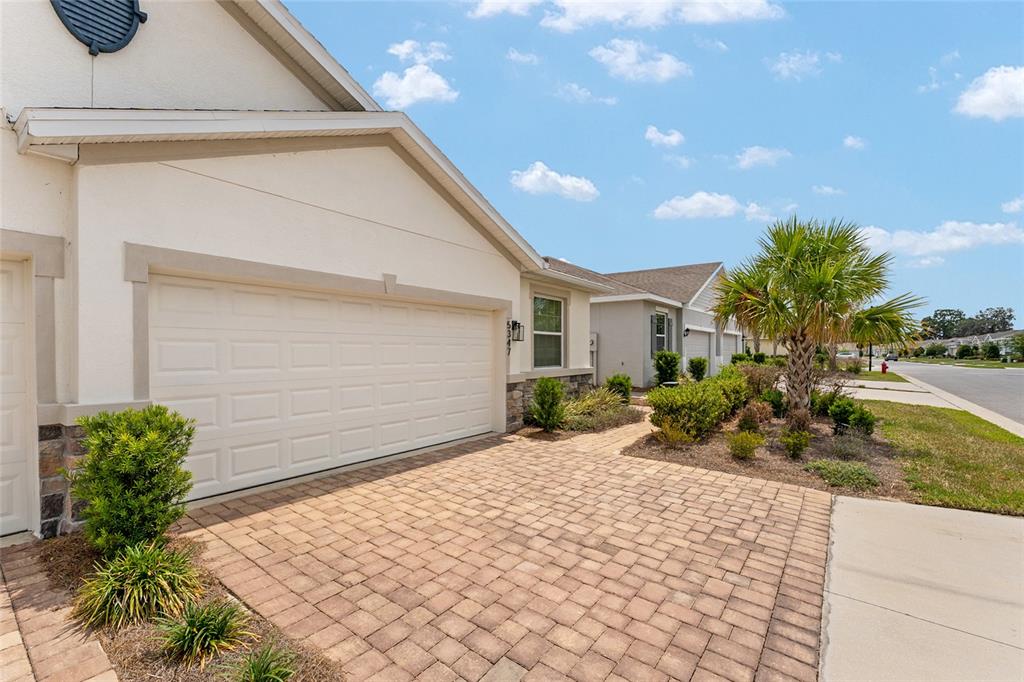 A paved driveway leads to the garage of a suburban home with a palm tree — 5347 NW 46TH LANE ROAD, OCALA, FL