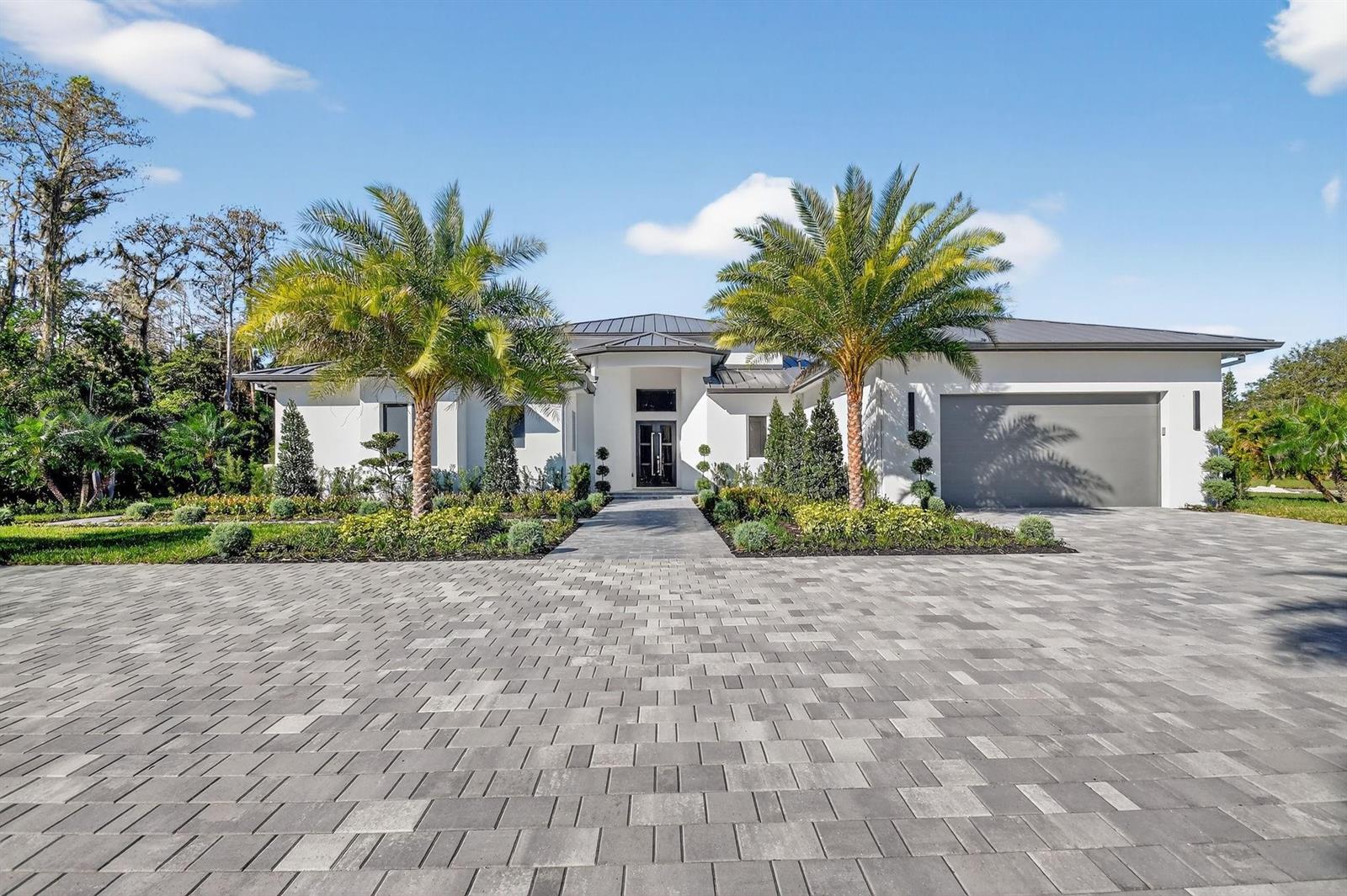 A modern white house with a metal roof, palm trees, and a large paver driveway — 6401 Park Lane W, Lake Worth FL 33449, LAKE WORTH, FL