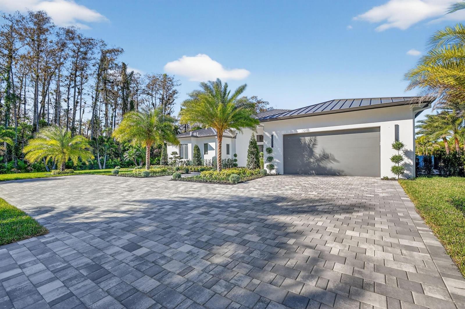 A modern white house with a gray garage door and a large paved driveway — 6401 Park Lane W, Lake Worth FL 33449, LAKE WORTH, FL