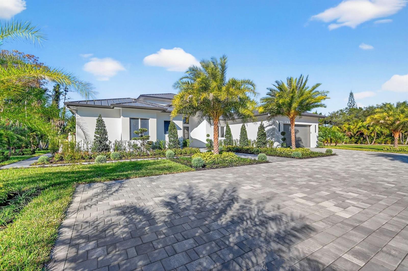 A modern white house with a metal roof and palm trees sits behind a paver driveway — 6401 Park Lane W, Lake Worth FL 33449, LAKE WORTH, FL