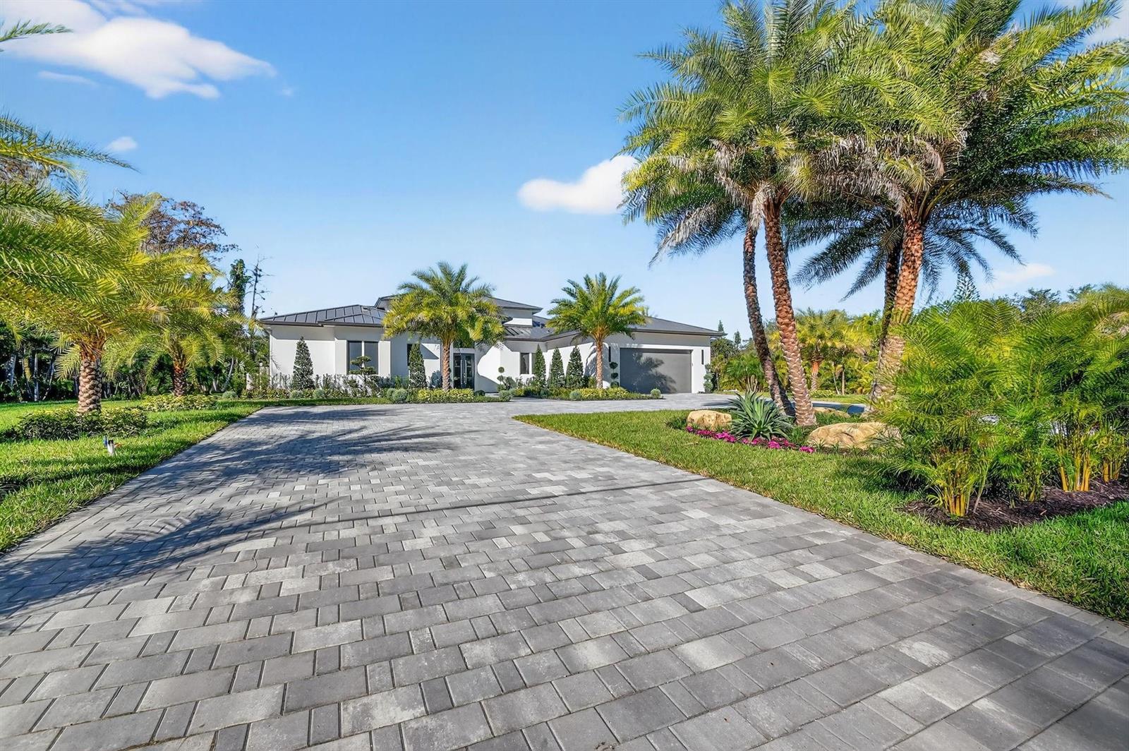 A modern single-story house with a paved driveway and palm trees under a blue sky — 6401 Park Lane W, Lake Worth FL 33449, LAKE WORTH, FL