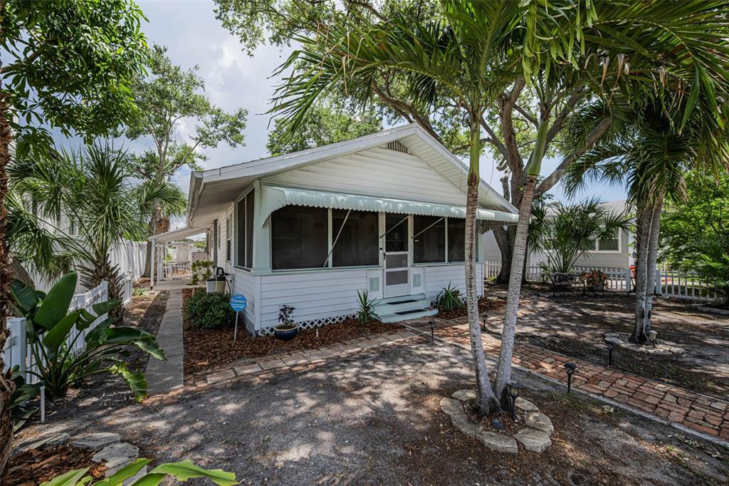 A white cottage with a screened-in front porch and a brick walkway under palm trees — 3829 2ND AVENUE N, ST PETERSBURG, FL