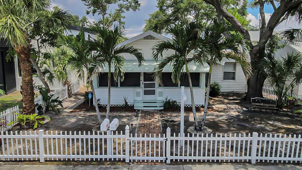 A white cottage with a brick walkway and a white picket fence in the front yard — 3829 2ND AVENUE N, ST PETERSBURG, FL