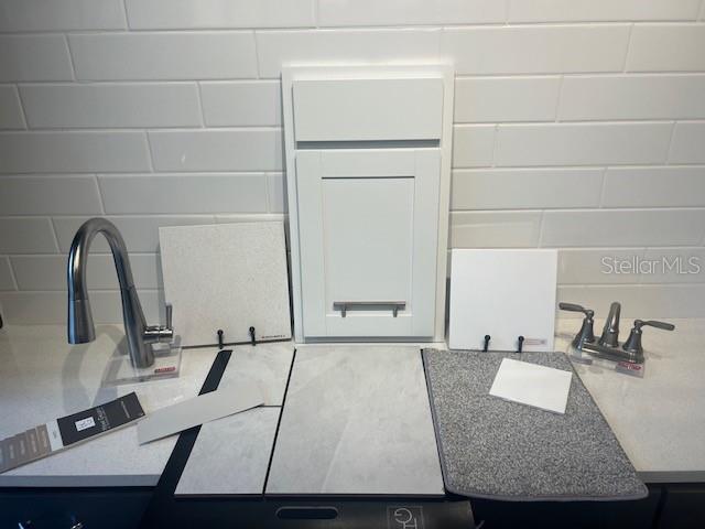 A display of interior design samples featuring white cabinetry, quartz countertops, tile, and plumbing fixtures — 14534 BANKS COURT, PARRISH, FL