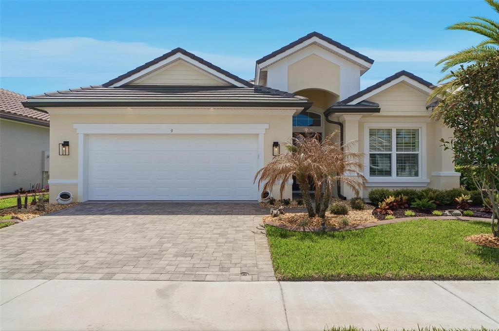 A single-story house with a two-car garage, beige stucco exterior, and a paved driveway — 9 DEL PALMA DRIVE, PALM COAST, FL