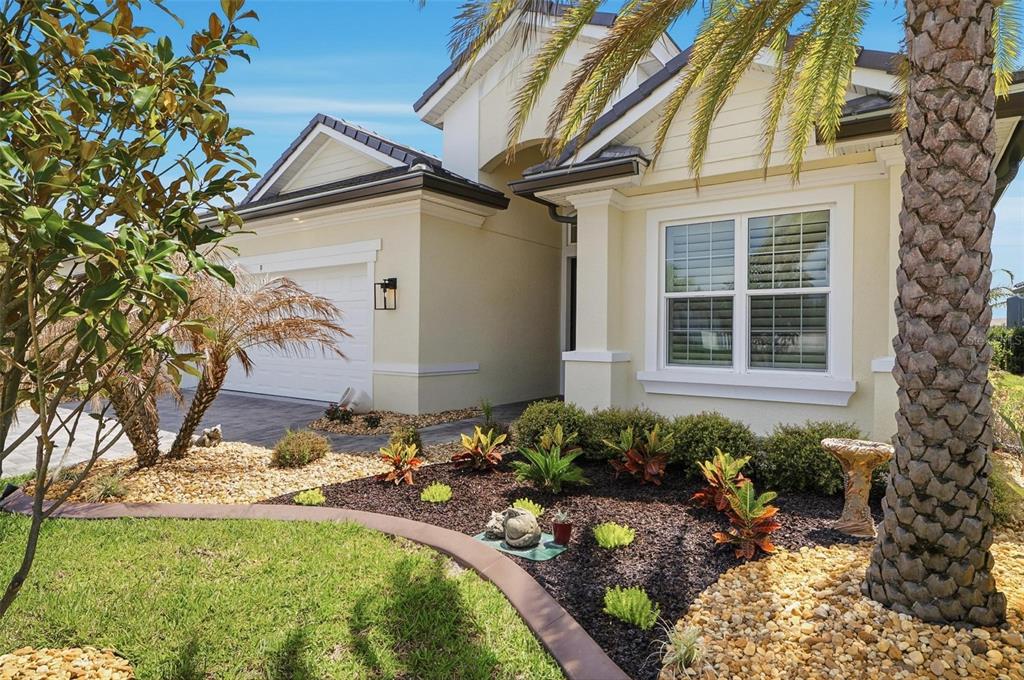 A single-story house with a beige exterior, a two-car garage, and landscaped front garden beds — 9 DEL PALMA DRIVE, PALM COAST, FL