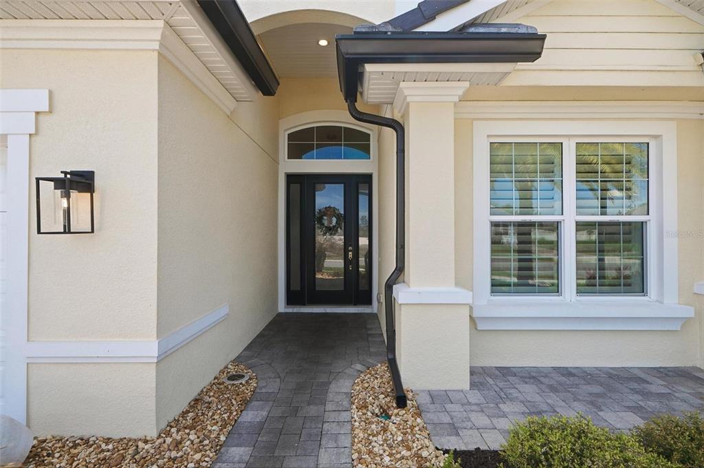 A front entryway features a dark door, a paved walkway, and a beige stucco exterior — 9 DEL PALMA DRIVE, PALM COAST, FL
