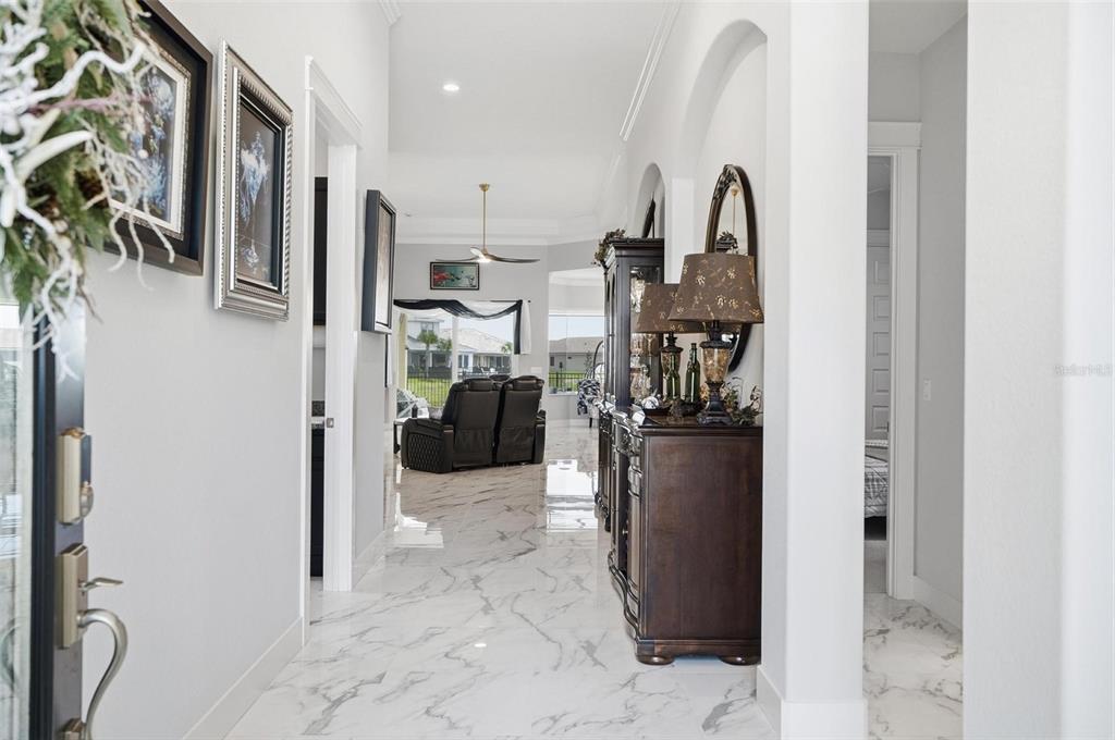 A bright foyer with white marble floors leads into a living area with dark furniture — 9 DEL PALMA DRIVE, PALM COAST, FL
