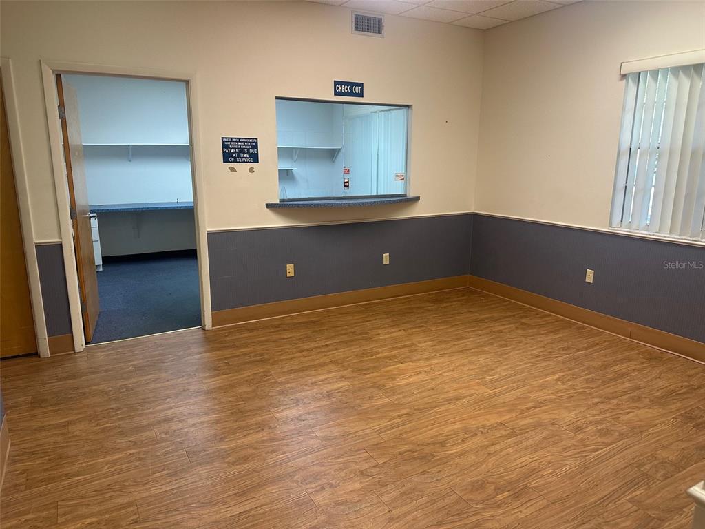 An office reception area features wood-look flooring, a checkout window, and a blue wainscot wall — 4611 NW 53RD AVENUE UNIT B, GAINESVILLE, FL