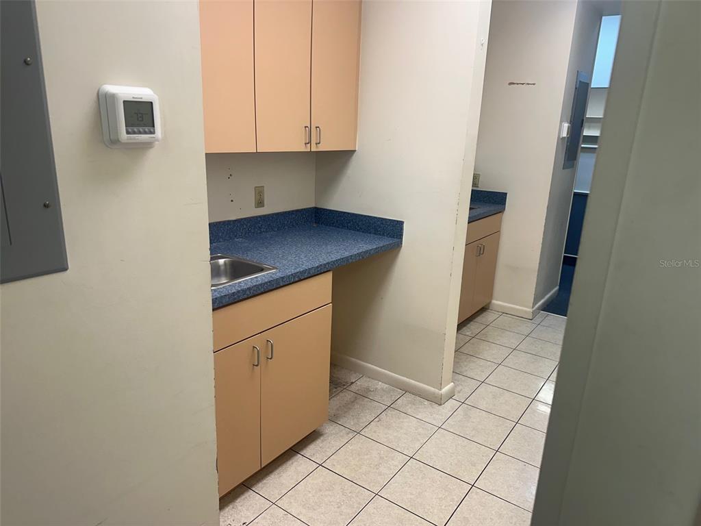 A small kitchenette features light-colored cabinets, a blue laminate countertop, and a tiled floor — 4611 NW 53RD AVENUE UNIT B, GAINESVILLE, FL