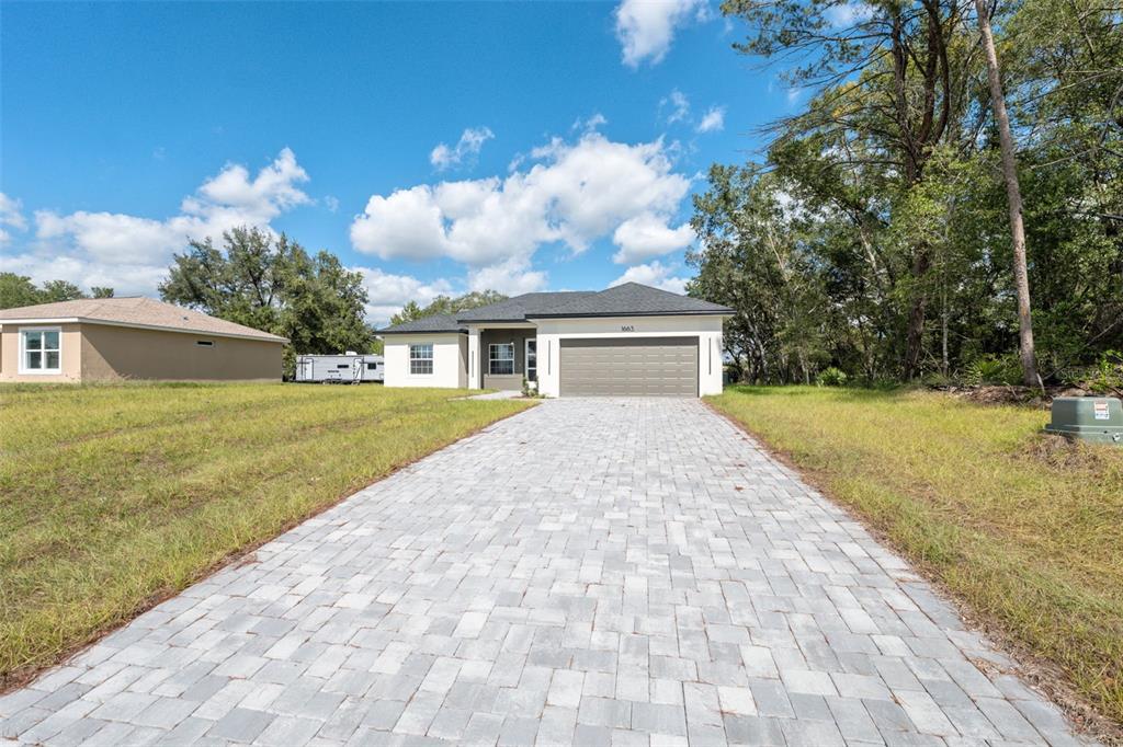 A single-story house with a paved driveway, a two-car garage, and a white exterior — 1663 SW 167TH STREET, OCALA, FL